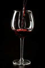 Red wine being poured in a wine glass on a dark background