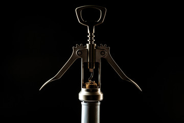 Bottle of wine and corkscrew over dark background