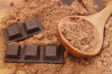 Chocolate bars on and cacao powder  with wooden spoon