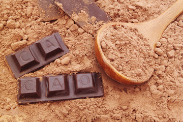 Chocolate bars on and cacao powder  with wooden spoon