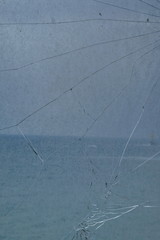 La mer vue à travers une vitre dépolie sale fêlée.
