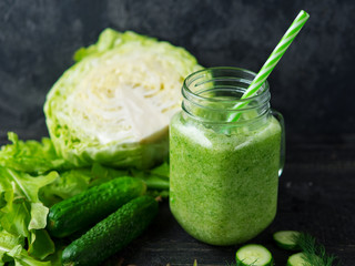 Green smoothie with cucumber, cabbage and healthy greens on the table