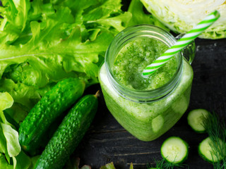 Green smoothie with cucumber, cabbage and healthy greens on the table