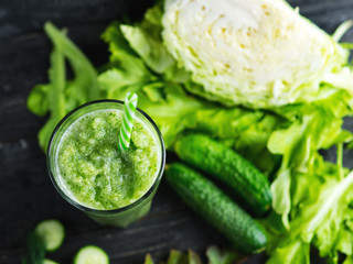 Green smoothie with cucumber, cabbage and healthy greens on the table