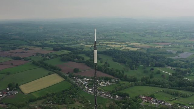 Orbiting aerial shot circling the tip of a television broadcast station antenna mast overlooking the Vale of Glamorgan in Cardiff South Wales.