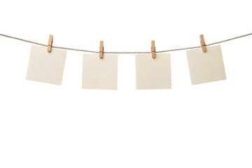 Four old paper blank notes hanging on the rope with wooden clothespins isolated on white background