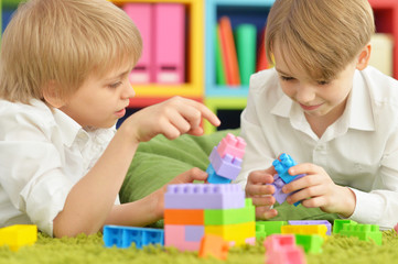 Two boys playing with colorful plastic blocks on floor