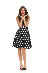 Smiling Beautiful Young Woman In Black Cocktail Dress In Polka Dots Is Holding Head In Hands