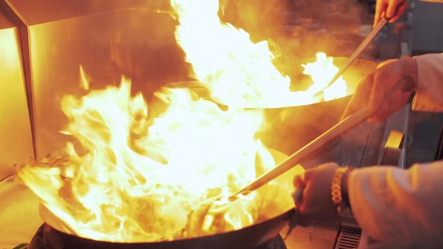 Slow motion of Chef Cooking in the Kitchen, Restaurant wok fire cooking Close up, cook frying vegetable in the commercial kitchen. Chinese style Sichuan food cooking 4k clip