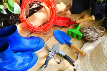 Gardening tools on wooden board with pruning shears rope rubber boot garden trowel equipment and...