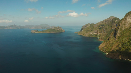 Fototapeta premium Seascape with tropical bay, rocky islands, ocean blue water, aerial view. islands and mountains covered with tropical forest. El nido, Philippines, Palawan. Tropical Mountain Range