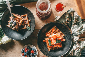 Belgian waffles with berries, ice cream and chocolate. Breakfast table setting. Morning lifestyle concept.
