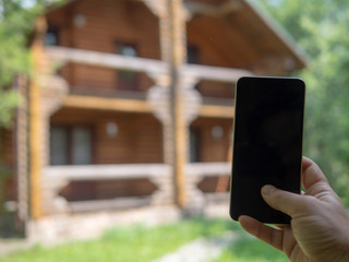 Hand with a phone in the background of a country house
