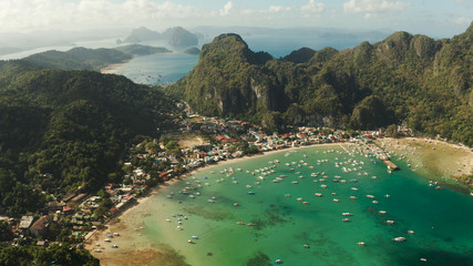 Many boats in the turquoise lagoon near city El nido, aerial view. Seascape with blue bay and boats view from above. Palawan, Philippines. traditional Filipino wooden outrigger boat called a banca