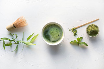 Ceremony green matcha tea and bamboo whisk on white concrete table. Top view. - obrazy, fototapety, plakaty