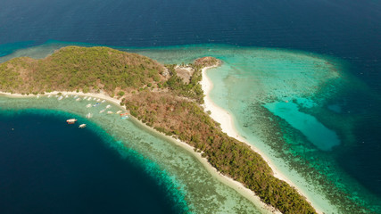 Obraz premium Aerial drone Island in blue lagoon with sandy beach and coral reef. Malcapuya, Philippines, Palawan. Tropical landscape with blue lagoon, coral reef