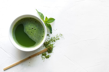 Ceremony green matcha tea and bamboo whisk on white concrete table. Top view.