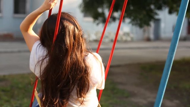 Sad girl swinging on a swing from side to side