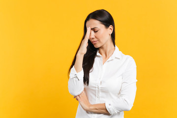 Portrait of crying upset young woman in white shirt keeping eyes closed, putting hand on nose isolated on bright yellow orange wall background in studio. People lifestyle concept. Mock up copy space.