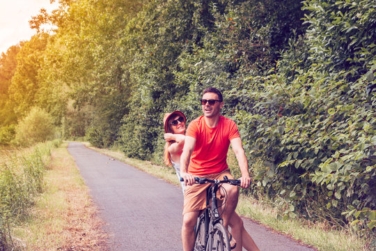 happy couple biking on a summer sunny day in a beautiful nature - healthy lifestyle, leisure activity, holiday, relationship concept