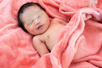 Newborn baby girl sleeping in pink cloth.