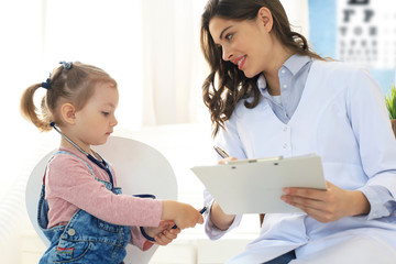 Little girl at the doctor for a checkup. Child auscultate the heartbeat of the doctor.