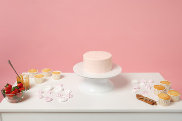 Obraz na płótnie Canvas Chef cook confectioner baker white table isolated on pink pastel background in studio. Nude cake with sweet rose cream without decoration, meringue pavlova. Mock up copy space food concept. Nobody.