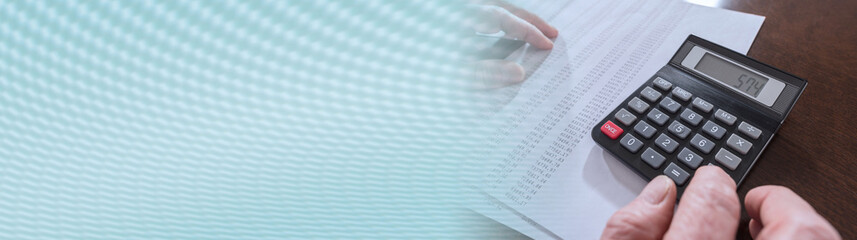 Male hand using calculator. panoramic banner