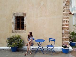 Beautiful woman sitting in cute vintage street. Crete, Greece