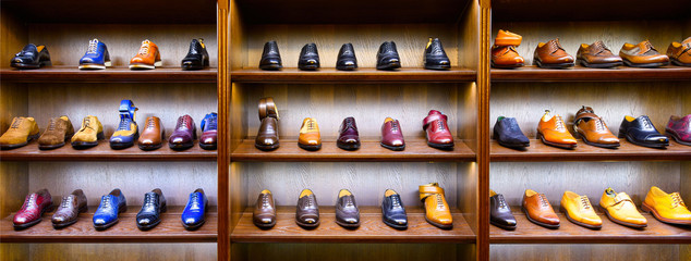 Full grain leather shoes on wooden display in men shoes boutique store. Black, brown and other colors.