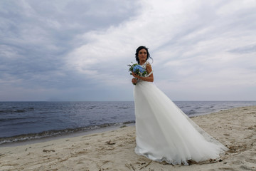 Fototapeta na wymiar portrait beautiful bride with a delicate wedding bouquet in her hands outdoors.cute young bride in lace dress on the shore. wedding day.wedding concept.