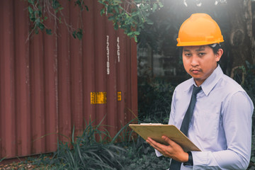 Male engineer inspection checking on container background With note on notepad or...