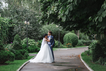 beautiful wedding couple at walk in green spring park. Wedding day in the summer outdoors. happy  bride and groom kissing and hugging in the green garden. newlyweds on nature