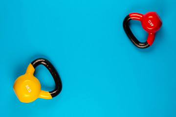 Two kettlebells of different sizes on blue background