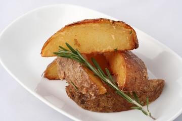 Home-baked potatoes. On a white plate close up. With a sprig of rosemary