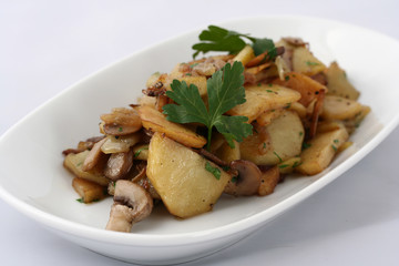  Fried homemade potatoes with onions and mushrooms. On a white plate on a white background
