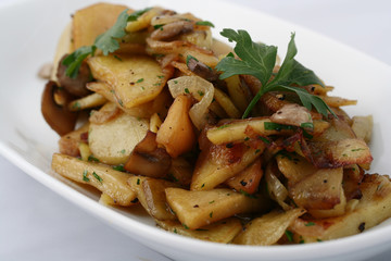  Fried homemade potatoes with onions and mushrooms. On a white plate on a white background