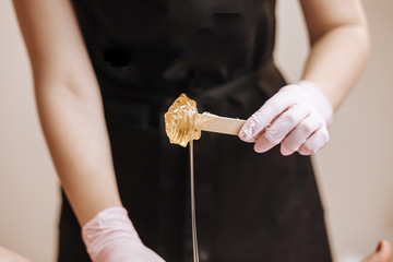 cosmetologist holding jar with wax for depilation