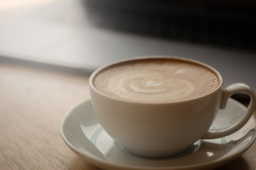 A cup of coffee on desk, Cup of coffee in hand, mug of latte coffee, Close up concept.