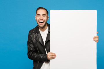 Handsome young bearded man hold big white empty blank billboard for promotional content isolated on blue wall background studio portrait. People sincere emotions lifestyle concept. Mock up copy space.