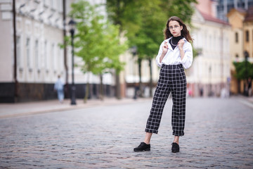 Fototapeta premium portrait of little beautiful stylish kid girl with sunglasses and short plaid pants in city urban street