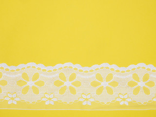 White lace on yellow background. Sewing still life