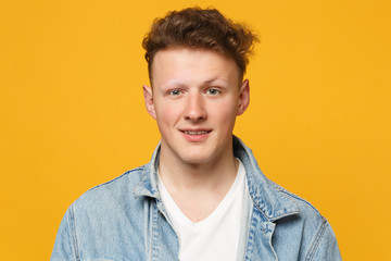 Portrait of smiling attractive young man wearing denim casual clothes looking camera isolated on yellow orange wall background in studio. People sincere emotions lifestyle concept. Mock up copy space.