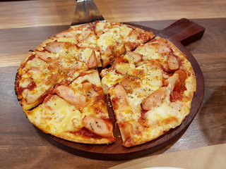 Sausage and pineapple pizza on a wooden pan