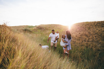 Happy parents and children hugging and having fun outdoors in a wheat field. Sunset