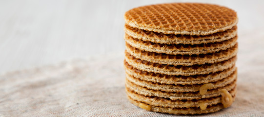 Stack of homemade Dutch stroopwafels with honey-caramel filling on cloth, low angle view. Space for text.
