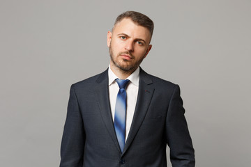 Handsome successful confident young business man in classic black suit shirt posing isolated on grey wall background, studio portrait. Achievement career wealth business concept. Mock up copy space.