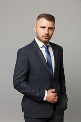 Handsome successful confident young business man in classic black suit shirt posing isolated on grey wall background, studio portrait. Achievement career wealth business concept. Mock up copy space.