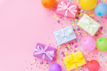 Gift or present boxes, colorful balloons and confetti on pink pastel table top view. Birthday party background. Banner format.