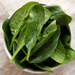 Fresh spinach in a bowl, overhead view. Top view, flat lay, from above. Close-up.